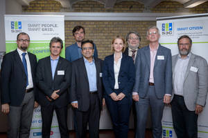 Speakers of the conference standing in front of a transparent